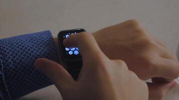 Man hand in watch with program on the screen against the background of table. Man hand at the home with watch and app on the screen. Man working with smart watch in office video