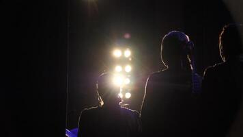 Silhouette of actors in the spotlight. Artists on stage close-up. Modern performance video