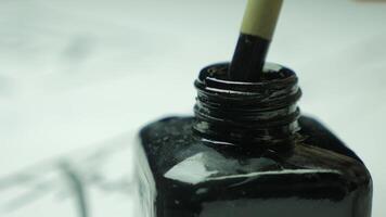 Detail von ein Chinesisch Bürste Trinkgeld eingetaucht im ein reflektierend Tinte Oberfläche im schwarz Krug. schließen oben zu Bürste und Tinte. Kalligraphie Bürsten mit Chinesisch Tinte video