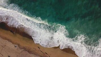 Sand beach. Stock. Top view of a beautiful sandy beach with the blue waves rolling into the shore. Sea background video