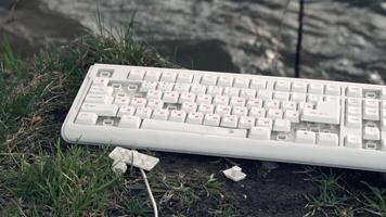 marteau fracasse une ordinateur clavier. cassé ordinateur clavier dans la nature. le concept de la technologie négatif impact sur le monde video