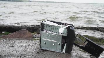 Concept of freedom from computer addiction - Man breaks system unit of a computer closeup, lake with forest background video