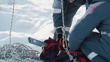 Due uomini nel uniforme mettere il utensili nel il Borsa avvicinamento. Due costruttore su il costruzione, neve sfondo video