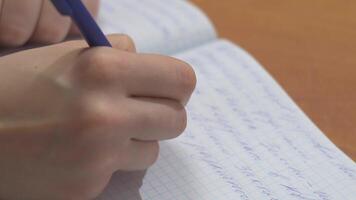 hembra manos con bolígrafo escritura en cuaderno. cerca arriba de mujer manos escritura en espiral bloc metido en de madera escritorio con varios artículos video