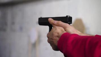 ley aplicación objetivo pistola por dos mano en academia disparo rango en llamarada. hombre dispara un pistola de cerca video