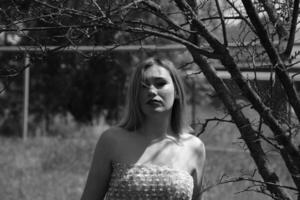 Black and white photo, girl in the garden on a meadow in a dress. photo