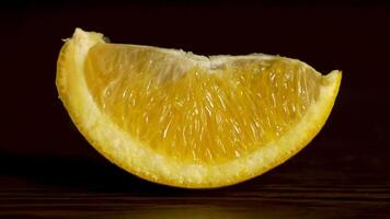 Juicy Fresh Fruit Orange Segments Against a Black Background. Fresh, juicy slice of orange rests on the table on a black background, the concept of proper nutrition video