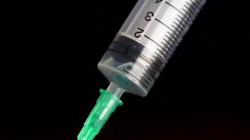 Taking vaccine into a glass syringe from a ampule on a black background. Closeup. Syringe is typed in turquoise fluid injection from illness serious illnesses, the concept of medicine video