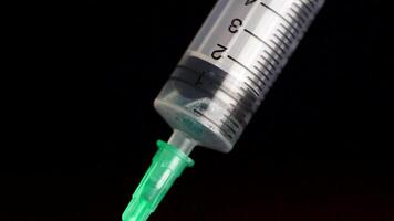 Taking vaccine into a glass syringe from a ampule on a black background. Closeup. Syringe is typed in turquoise fluid injection from illness serious illnesses, the concept of medicine video