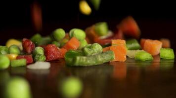 haché des légumes. tranches de rouge et vert poivrons, carottes, vert haricots, petits pois, oignon, blé chute sur noir Contexte. lent mouvement. haché des légumes tomber sur noir Contexte video