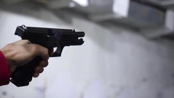 legge rinforzo scopo pistola di Due mano nel accademia tiro gamma nel bagliore. uomo spara un' pistola avvicinamento video