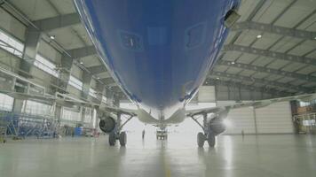 Airplane in hangar, rear view of aircraft and light from windows. Large passenger aircraft in a hangar on service maintenance video