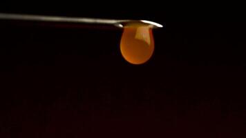 With a needle from a syringe dripping liquid, close-up. Blood flows from syringe on a black background. With a syringe dripping red liquid video