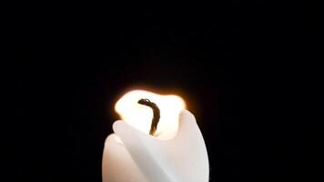 Candle flame closeup over black - Christmas. Candle is lit on a black background closeup. Brightly burning candle macro video