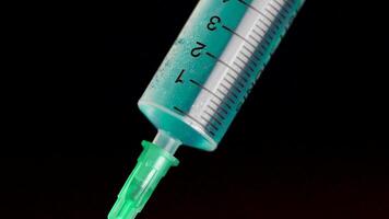 Taking vaccine into a glass syringe from a ampule on a black background. Closeup. Syringe is typed in turquoise fluid injection from illness serious illnesses, the concept of medicine video
