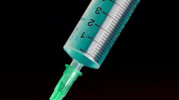 Taking vaccine into a glass syringe from a ampule on a black background. Closeup. Syringe is typed in turquoise fluid injection from illness serious illnesses, the concept of medicine video