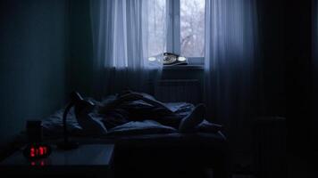 View of a man at night suffering from deep depression. Lonely man lying on the bed in the dark video