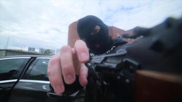 terrorista participación kalashnikov rifle. enmascarado hombre participación un kalashnikov rifle, toma objetivo y dispara delincuente con un pistola en el manos video