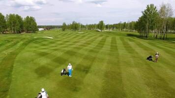 aéreo Visão golfe curso. golfistas caminhando baixa a fairway em uma curso com golfe saco e carrinho video