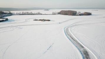 ett bil körning genom de vinter- skog på Land väg. topp se från Drönare. antenn se av snö täckt väg i vinter, bil godkänd förbi. topp se av de bil reser på snöig väg video