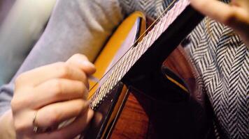 Closeup beautiful acoustic guitar being played by woman sitting down, musician concept. Woman playing the guitar closeup video