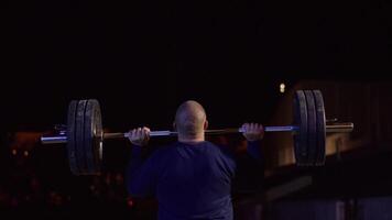 tyngdlyftare hissar de bar ovan hans huvud. styrka Träning med en enorm vikt. stark crossfit idrottare i de mitten en tung ryck hiss i en crossfit låda Gym video