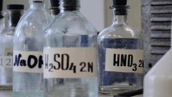 Bottles of solutions stored on shelf in laboratory. Bottles with chemical solutions of NaOH, H2so4 and HNO3. Sulfuric acid, sodium hydroxide, nitric acid video