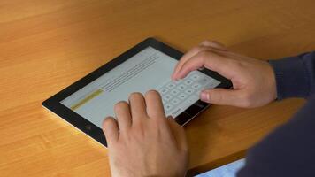 Close-up of male hands using modern digital tablet and computer at office, frontal view of businessman hands typing text information on touch screen of tablet pc video