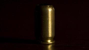 Bullet from the gun placed on a wooden table on black background, macro. One bullet on the table to protect or murder people video