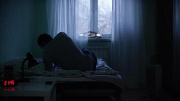 View of a man at night suffering from deep depression. Lonely man lying on the bed in the dark video