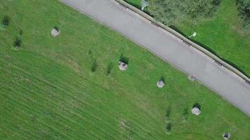 Grün Park und es ist riesig Rasenflächen auf ein sonnig Frühling Tag. Clip. Antenne von fliegend Drohne von ein Stadt Park mit Gehen Pfad und Grün Zone Bäume video