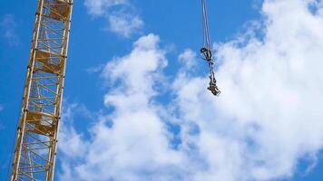 proche en haut de une Jaune et vert grue boom avec principale bloquer et foc contre une clair bleu ciel. la tour bâtiment grues contre le ciel. video