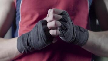 hombre flexionando su puños antes de un luchar. de cerca de un joven tailandés Boxer manos cáñamo cuerdas son envuelto antes de el lucha o capacitación. video