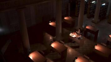 Top view of student hand writing a book with laptop at library. Girl sitting in empty library at night top view video