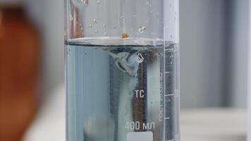 Fluid changes color after mixing. Close-up of colorful flask in which the liquid is mixed by a special device video