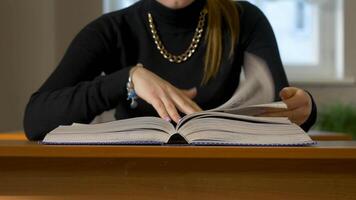 mulheres mãos folheando através uma livro. mulher sentado às a mesa folheando através a livro video