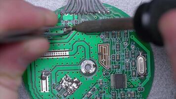 Hand holding soldering gun and working with lead repair board electronic on top view. Male hands close up soldering a microchip. soldering iron video