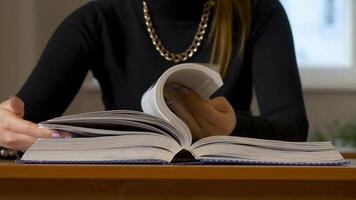 mulheres mãos folheando através uma livro. mulher sentado às a mesa folheando através a livro video