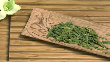 Glass teapot with blooming tea flower inside against wooden background Chinese green tea leaves close up in traditional cup. tea ceremony. Chinese tea, ceremony video