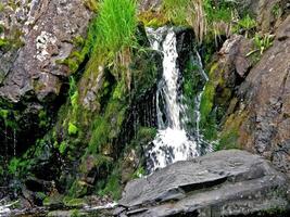 Waterfall from the thawed waters. Melting snow in the hilly tund photo