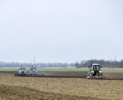 lozano y aflojar el suelo en el campo antes de siembra. el tractor arados un campo con un arado foto