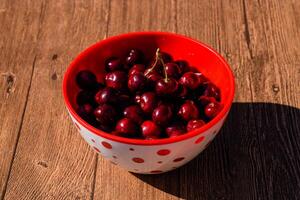 bayas de un dulce Cereza en un de madera antecedentes en un el plastico taza. maduro rojo dulce Cereza foto