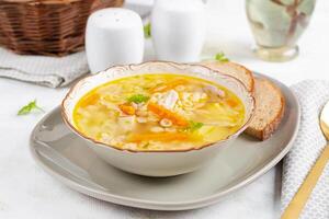 Fresh chicken soup with vegetables and stelline pasta in a bowl with carrot and parsley. photo