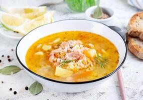 Fish soup with salmon, vegetables and rice in white bowl. Salmon soup. photo