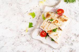 Grilled tortilla wraps with chicken and fresh vegetables on white wooden board. Chicken burrito. Mexican food. Healthy food concept. Top view photo