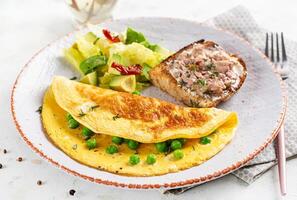 Omelette with green peas and toast with cod liver on white plate.  Frittata - italian omelet. photo