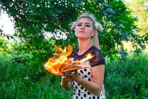 girl holds a burning book in her hands. A young woman in a forest burns a book. photo