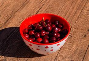 bayas de un dulce Cereza en un de madera antecedentes en un el plastico taza. maduro rojo dulce Cereza foto