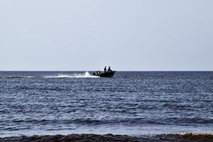 The boat rushes by the sea. In the boat people. Seascape in the evening. Silhouette of a motor boat and people in it against the background of the sea distance photo