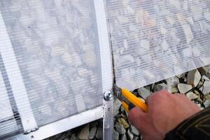 Cutting polycarbonate when installing it on the frame elements of the greenhouse. Greenhouse installation photo